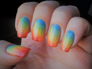 Unhas decoradas com as cores do arco-íris. Foto unhas com os dedos coloridos com vermelho, amarelo, verde e azul em formato degradê.