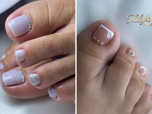 Francesinha no pé com pedrinhas. Foto mostra dois pés com unha franceisinha e pedrinhas brilhantes no topo da unha.